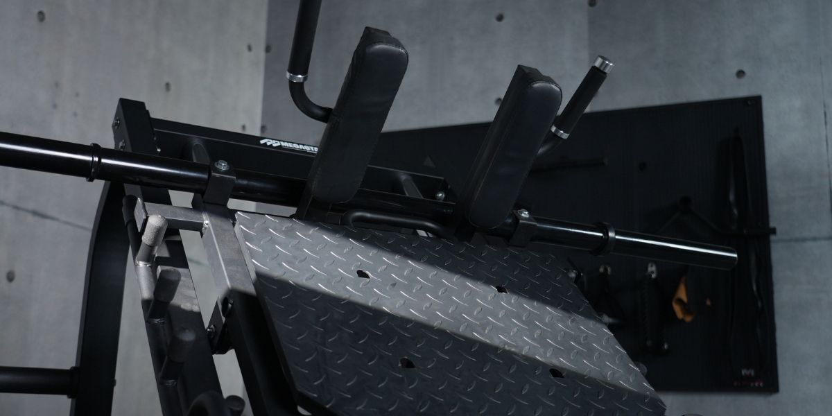 Close-up of the Megastar leg press machine, showing a diamond-plate footplate, padded shoulder supports, and a heavy-duty steel frame in a gym.