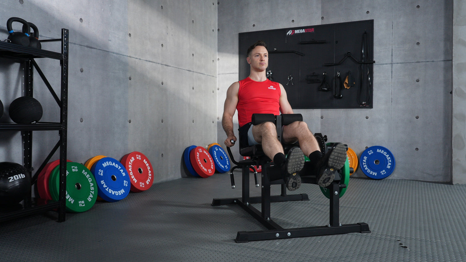 Man performing leg extension on a MEGASTAR Leg Extension Curl Machine in a modern gym, training quadriceps with controlled form.