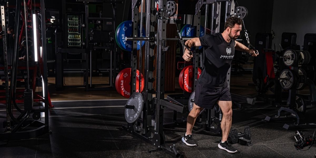 Man performing a cable crossover exercise on a functional trainer in a gym, with colorful weight plates in the background.