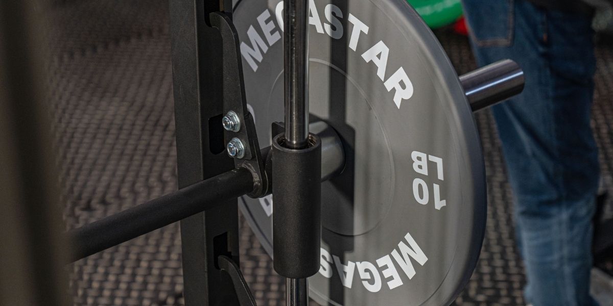 Close-up of MEGASTAR 10 lb plate on a guided bar, illustrating smith machine bar weight and safety stop.