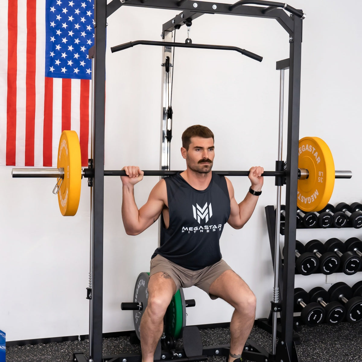 Man performing a back squat in a power rack using yellow MEGASTAR Bounce Bumper Plates, demonstrating stable form and a home-gym strength training setup.