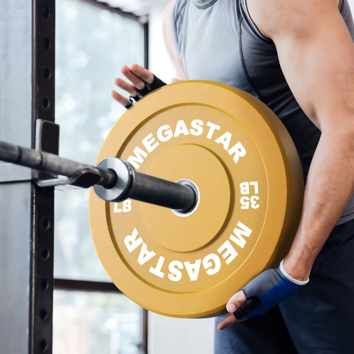 Athlete loading a 35 lb plate from the MEGASTAR Bounce Bumper Plates set onto a barbell in a gym.