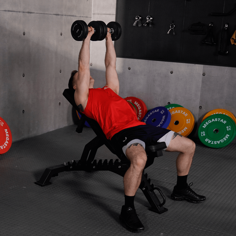Man performing a dumbbell chest press on an adjustable home gym weight bench, using adjustable weights.